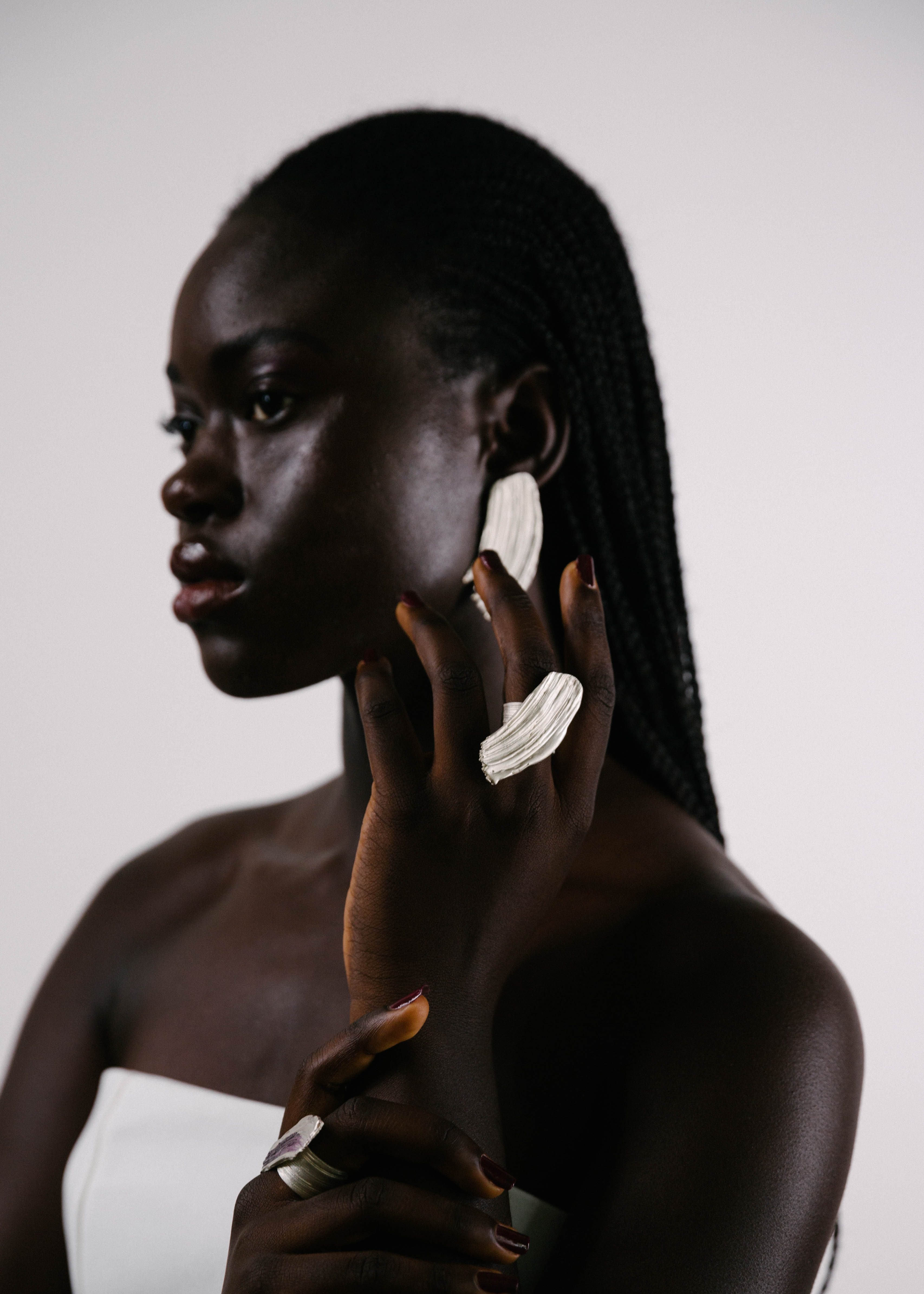 Woman wearing large handcrafted silver earrings and ring against a plain background