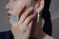 Close-up of a model wearing a handcrafted silver helios ring and touching their face with their hand.