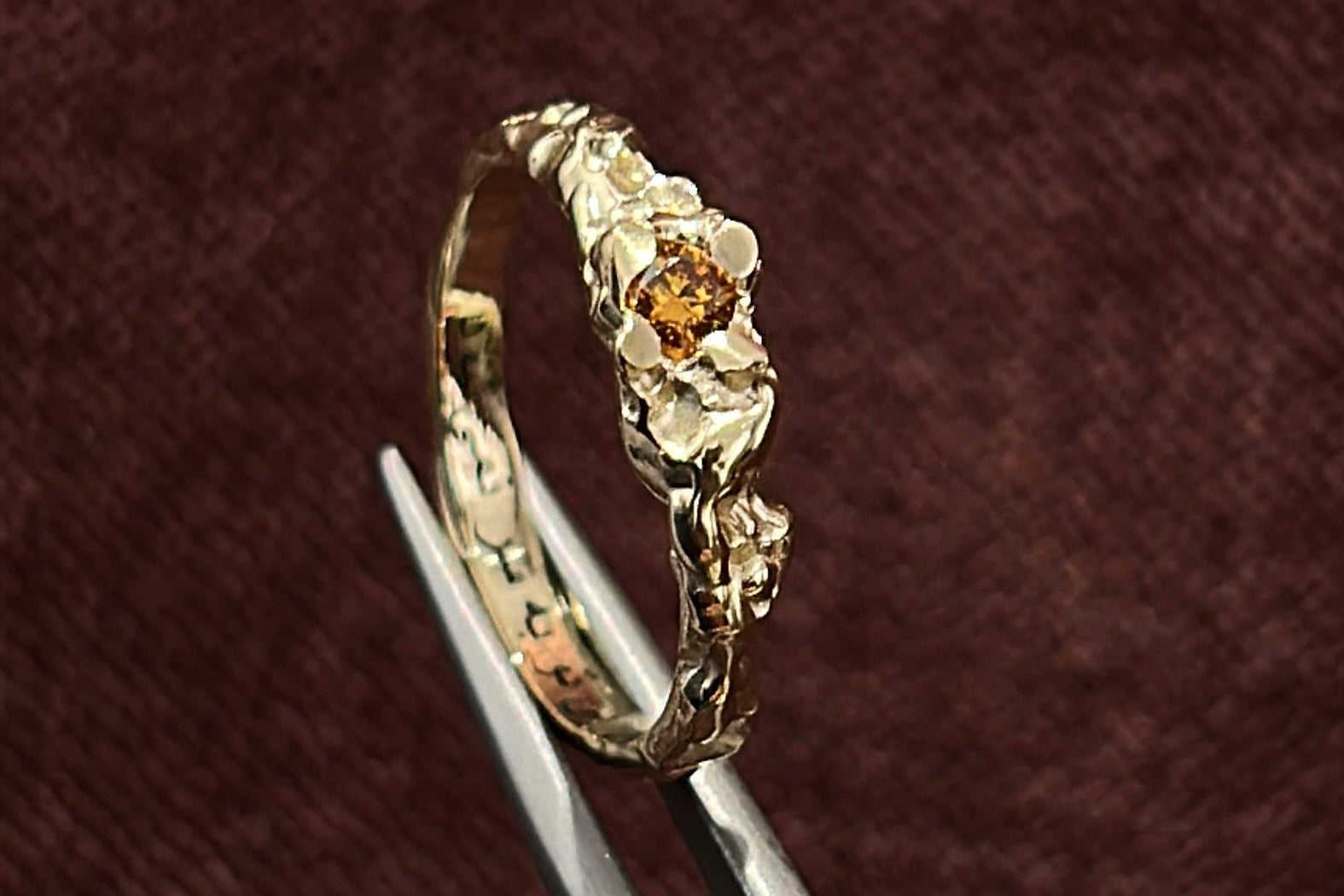 Gold ring with a small gemstone on a dark red velvet background