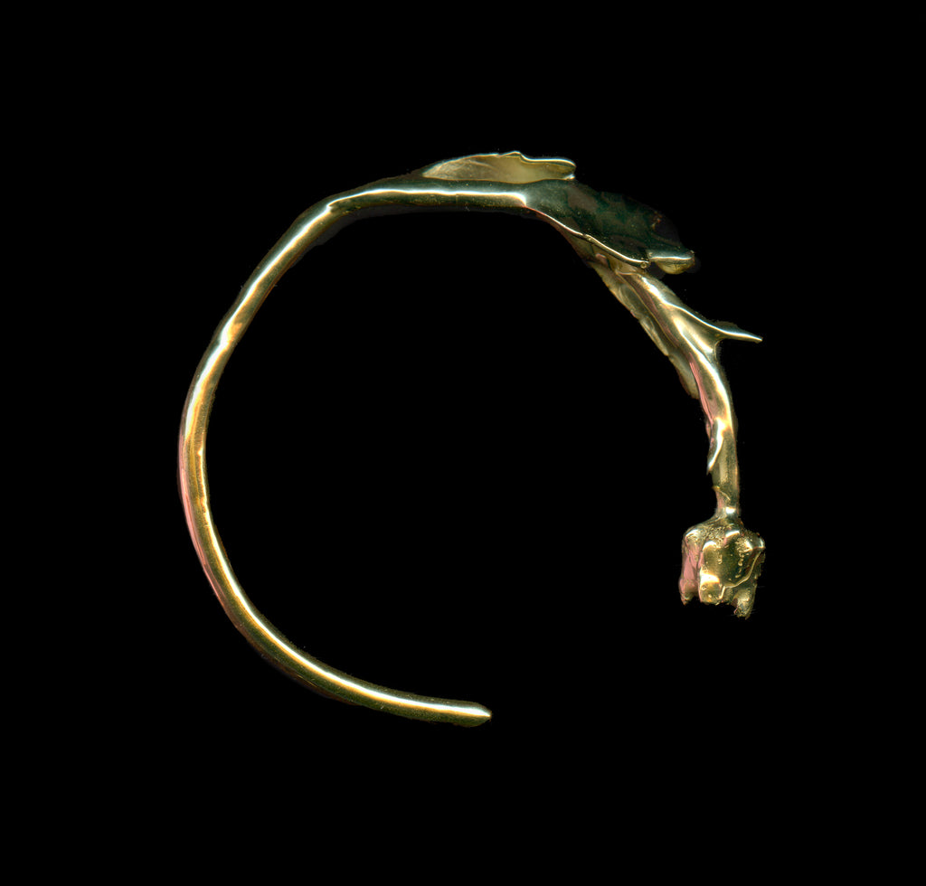 Handcrafted gold florero bracelet on black background
