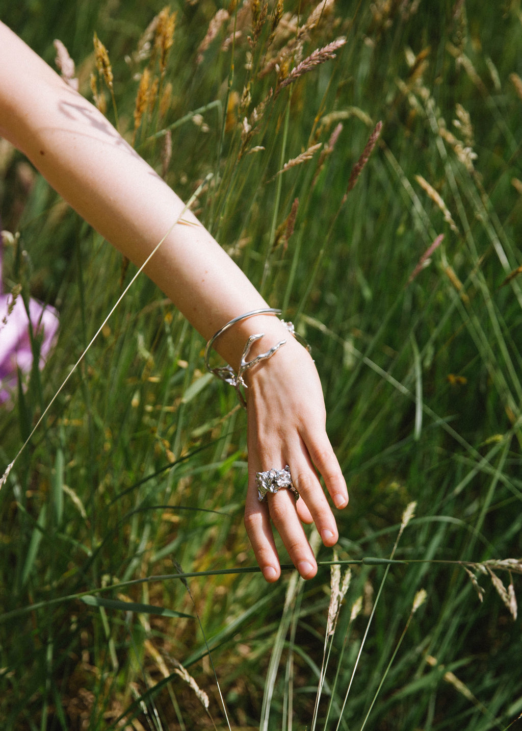 hand in greeen nature waering a handcrafted silver bracelet and ring