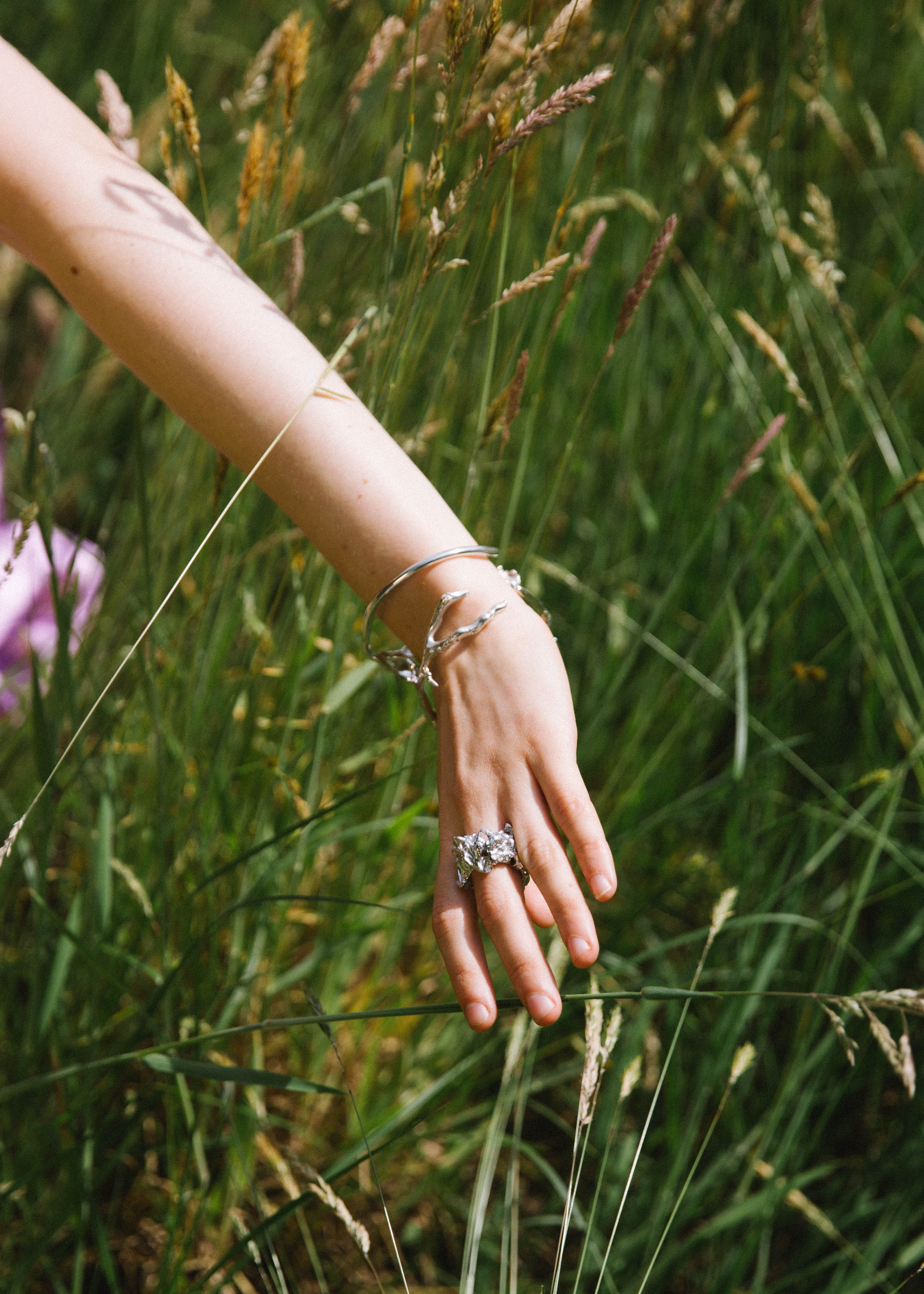 hand in greeen nature waering a handcrafted silver bracelet and ring