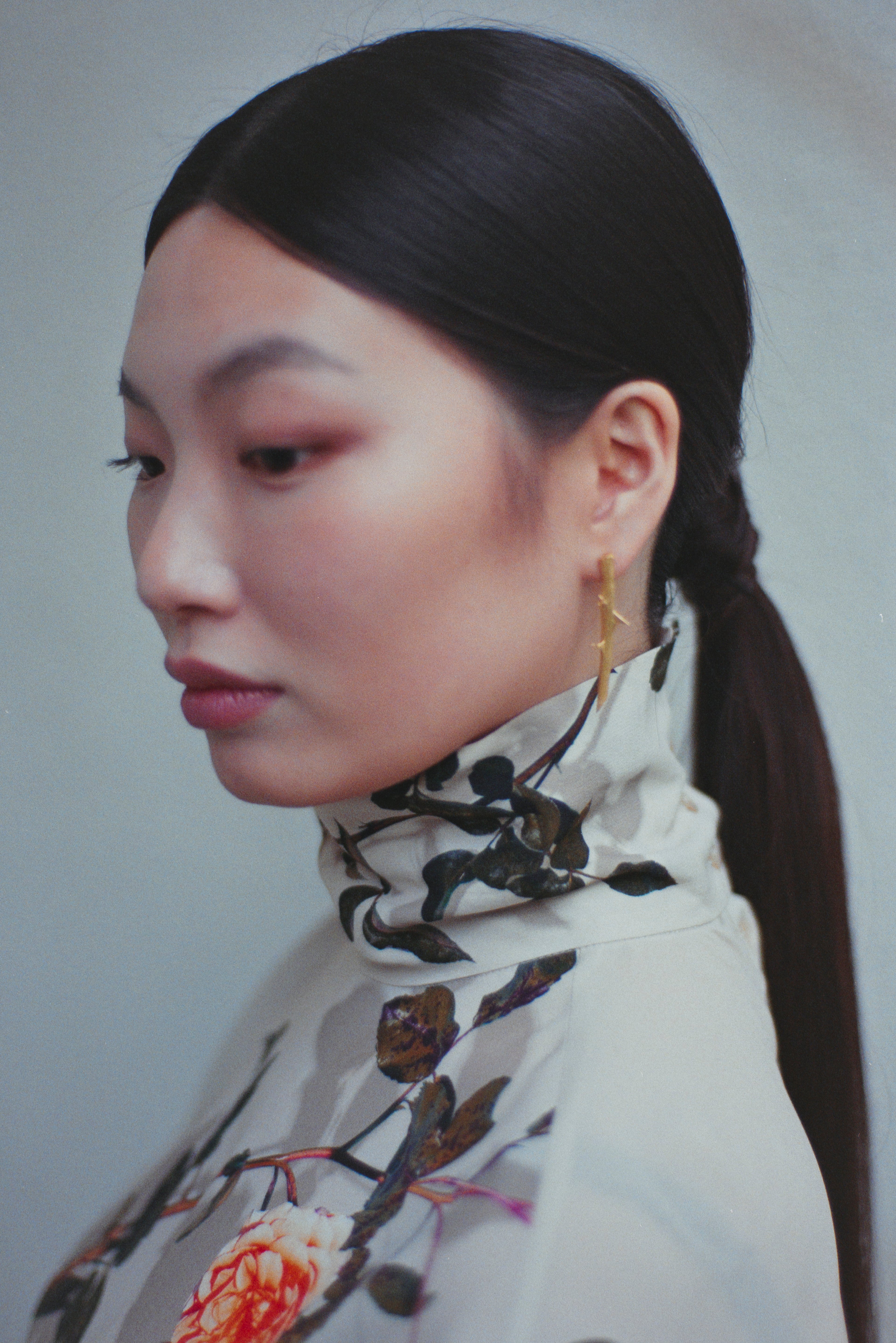 Woman wearing a floral scarf with a plain background on her ears handcrafted gold earrings