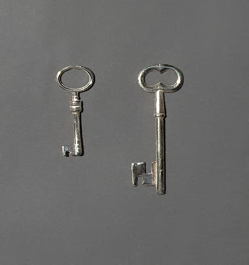 Two handcrafted silver keys on a dark gray background