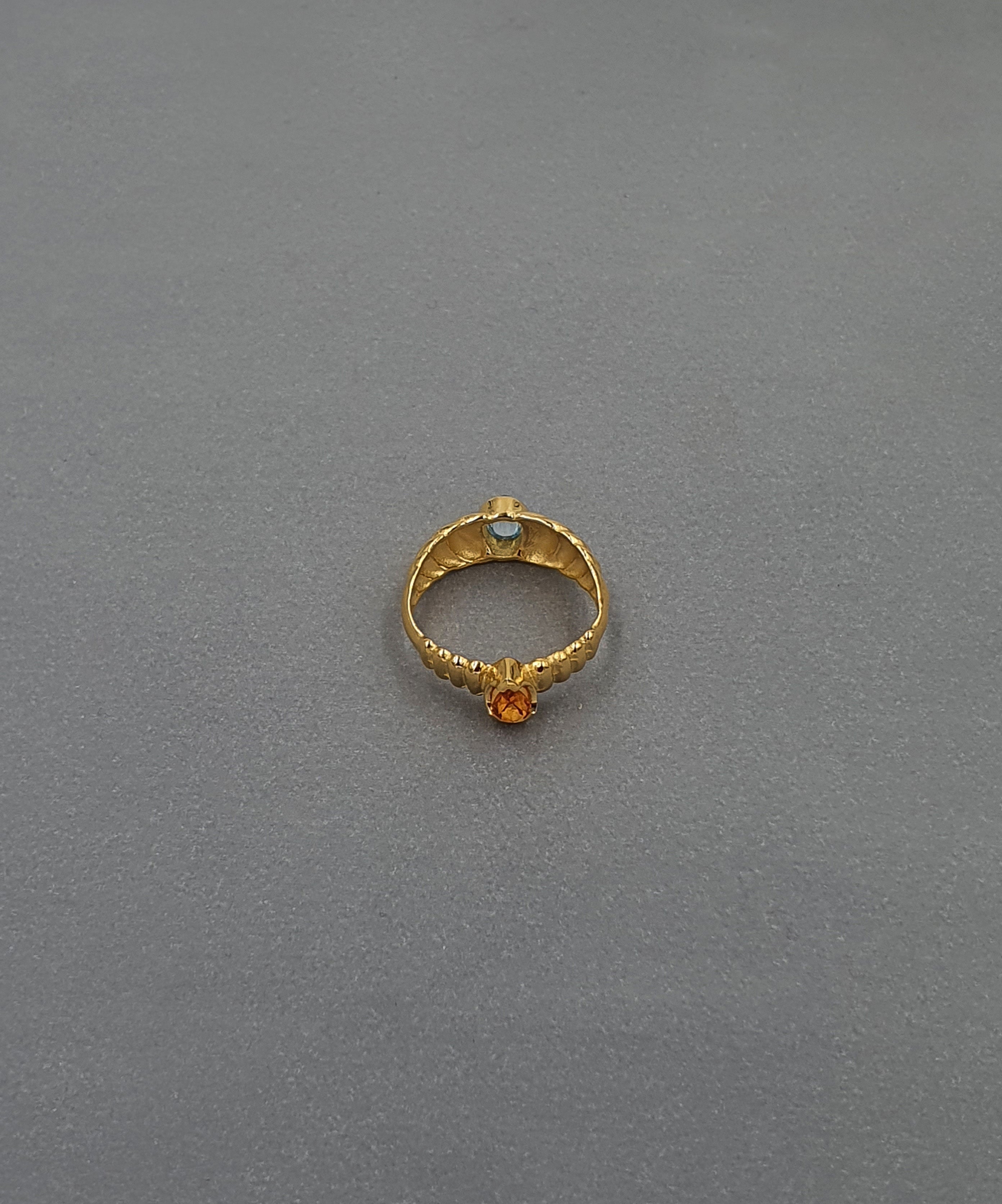 handcrafted gold ring on grey background