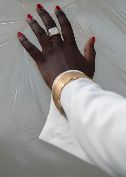 Handcrafted silver ring and a gold bracelet worn by a model with red nailpolish