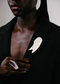 Handcrafted silver brooch worn on a black blazer with a silver ring with purple details on it