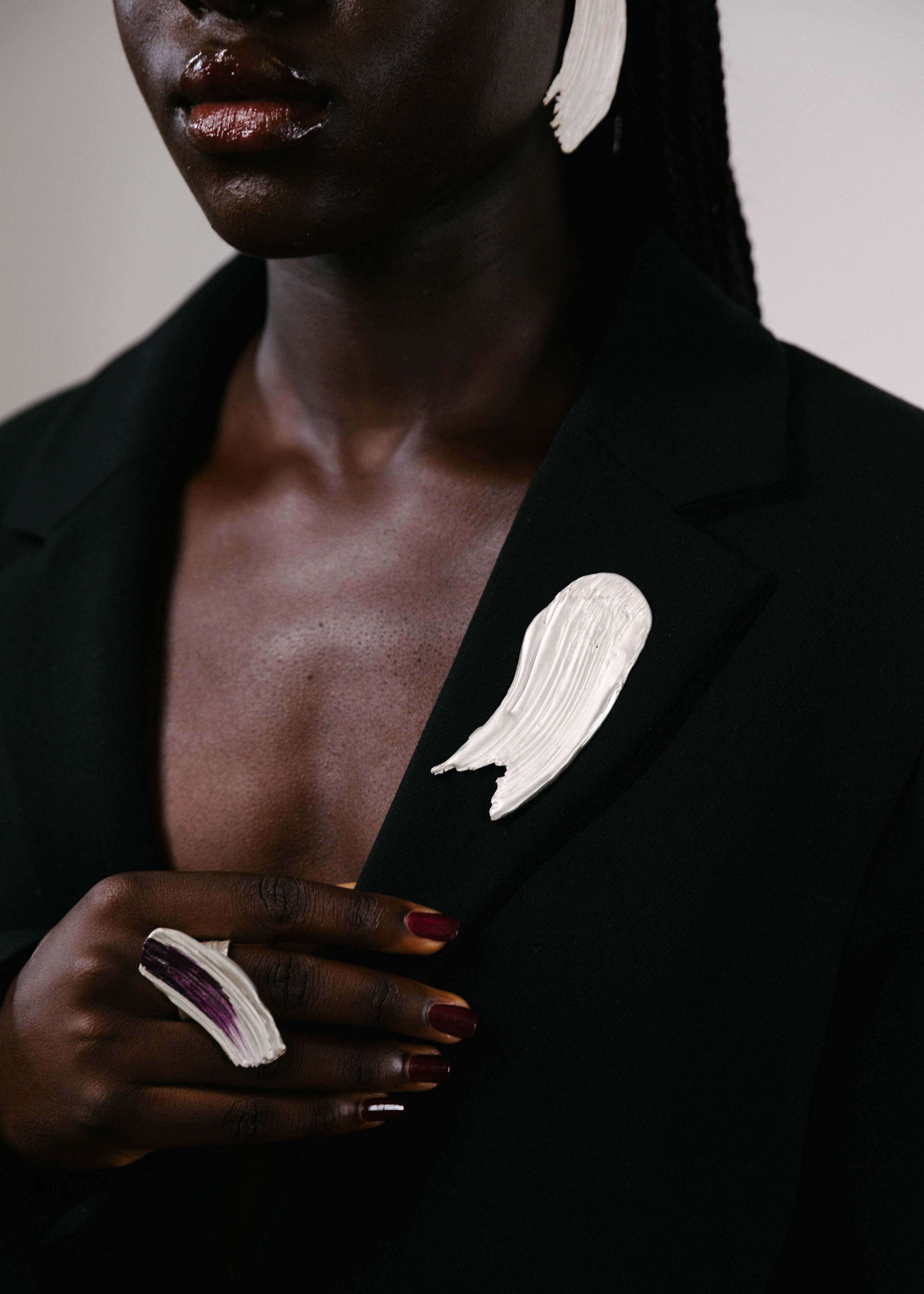 Handcrafted silver brooch worn on a black blazer with a silver ring with purple details on it