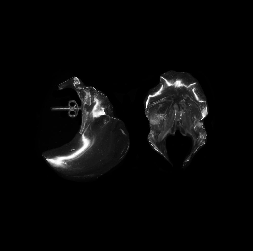 Pair of handcrafted silver orchid earrings on a black background